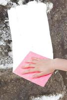 hand deletes melting snow by pink rag photo