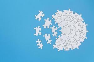 Unfinished white jigsaw puzzle pieces on blue background,  Copy space. photo