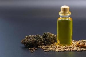 semillas de cáñamo y aceite de cáñamo en un frasco de vidrio sobre un fondo negro. concepto de marihuana medicinal, aceite de cannabis cbd. foto
