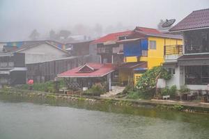 edificio del pueblo etong en la niebla y el lago frente al pueblo en la ciudad de kanchanaburi, tailandia. mina pilok la antigua mina cerca de la frontera entre Tailandia y Myanmar foto