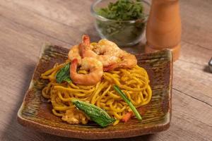 Fried noodles with shrimp in a plate on the table photo