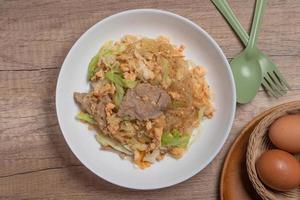 Stir fried vermicelli with pork, egg and collard greens in a white plate. photo