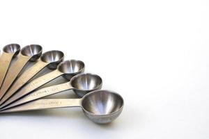 vista superior utensilios de cocina cucharas medidoras de acero sobre fondo blanco. foto