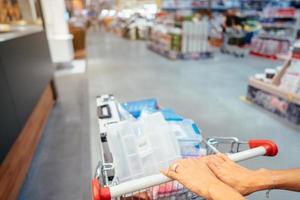 Human Hand Close Up With Shopping Cart in a Supermarket Walking Trough the Aisle photo