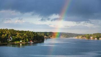 panorama of green coast with villages and rainbow photo