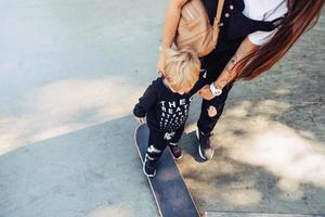 Young mother teaches her little boy to ride a skateboard photo