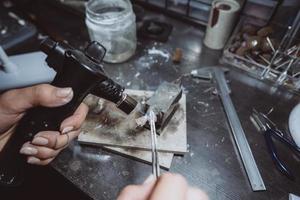 In the workshop, a woman jeweler is busy soldering jewelry photo