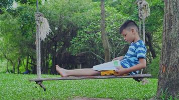 chica asiática y hombre leyendo un libro en un columpio video