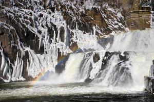 rainbow on river dam cascade in winter photo