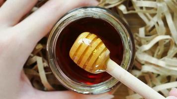 Honey dipper with honey on wood background with paper shreds. Close up macro shot. video