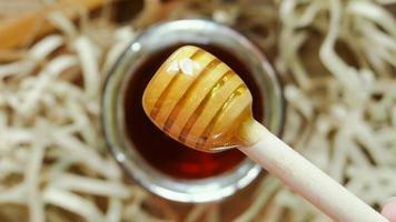 Honey dipper with honey on wood background with paper shreds. Close up macro shot. video