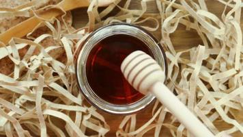 Honey dipper with honey on wood background with paper shreds. Close up macro shot. video