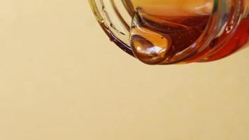 Close up shot of honey pouring out of glass jar. Health and beauty product sustainable lifestyle concept.