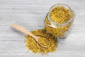 above view of jar and spoon in bee pollen on gray photo