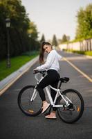 Beautiful girl posing at white bicycle. Walk in nature. photo