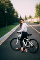 Beautiful girl posing at white bicycle. Walk in nature. photo