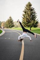 Woman athlete leaping somersault on the road, doing exercises outdoors. photo