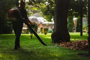A woman operating a heavy duty leaf blower. photo