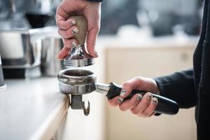 Barista presses ground coffee using tamper. photo