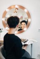 Attractive woman at the mirror in beauty studio photo