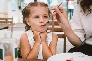 Young mom eating cake with smiling kid on the street photo