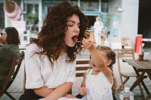 mamá joven comiendo pastel con un niño sonriente en la calle foto