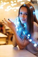 Woman holding glowing christmas garland in hands photo