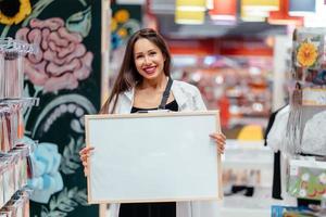 mujer morena sonriente sosteniendo tablero en blanco blanco foto