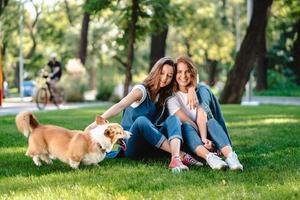 dos amigas en el parque juegan con un perrito foto