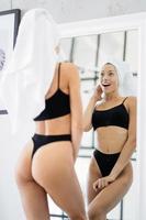 Woman in the bathroom with a towel on her head in front of a mirror. photo