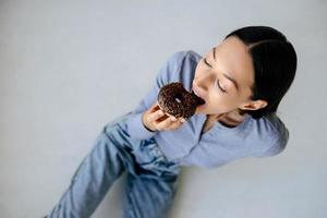 Portrait of rejoicing woman eats tasty donut at home. photo