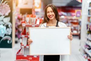 Smiling brunette woman holding white blank board photo