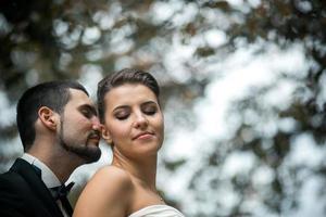 groom embracing bride from back photo