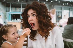 Young mom eating cake with smiling kid on the street photo