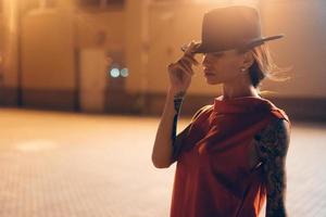 The young, attractive girl in a hat poses to the camera at night photo