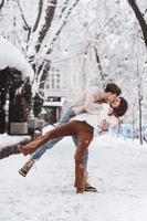 un chico joven y una chica hermosa se divierten en una calle nevada foto