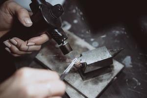 In the workshop, a woman jeweler is busy soldering jewelry photo