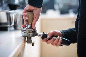 Barista presses ground coffee using tamper. photo