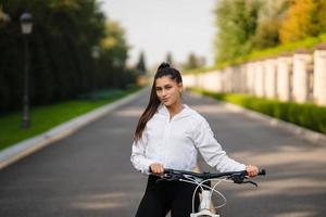 Beautiful girl posing at white bicycle. Walk in nature. photo