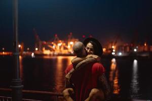 Guy and girl hugging each other on a background of the night port photo