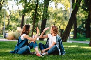 Felices amigas levantando la mano dando cinco en el parque de la ciudad foto