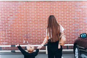 Back view of mother and her little son against the backdrop of a brick wall photo