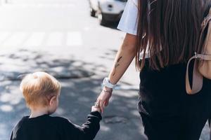 Back view of mother and her little son outdoors in city photo