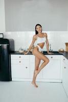 Beautiful young girl posing in lingerie in the kitchen photo