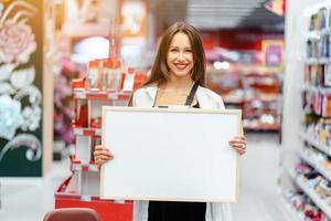 Smiling brunette woman holding white blank board photo