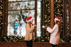 The girl gives a gift to her female friend on the street. photo