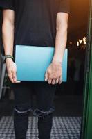 Guy with a closed laptop in hand, indoors photo