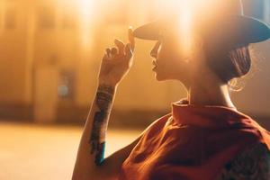 The young, attractive girl in a hat poses to the camera at night photo