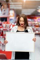 Smiling brunette woman holding white blank board photo