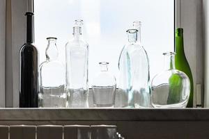 varias botellas borrachas vacías en el alféizar de la ventana de casa foto